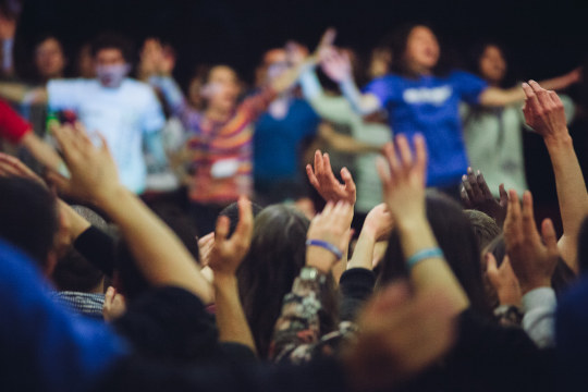 A crowd of people with their arms in the air.